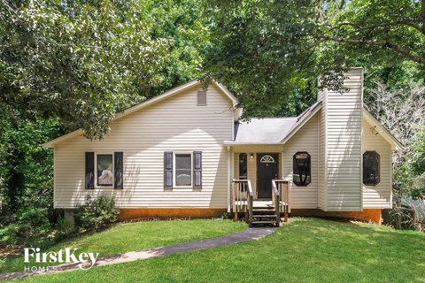 a small white house with a yard and trees
