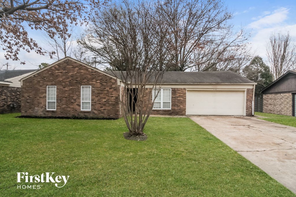 front view of a brick house with a lawn and a tree