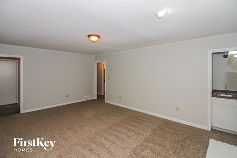 a living room with a carpet and a door to a kitchen