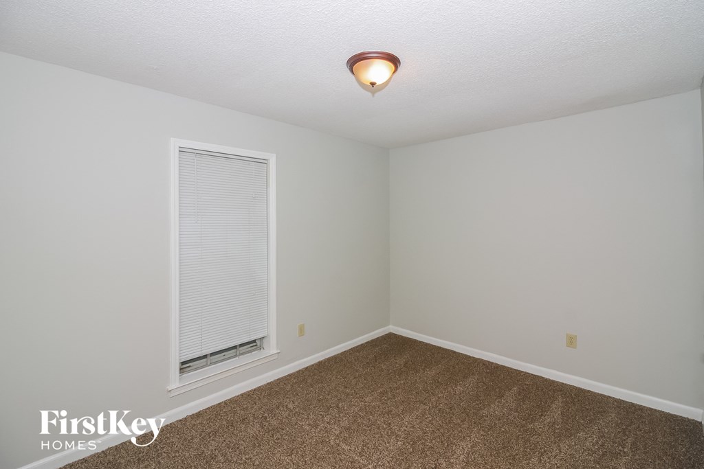 a bedroom with a large window and a carpeted floor