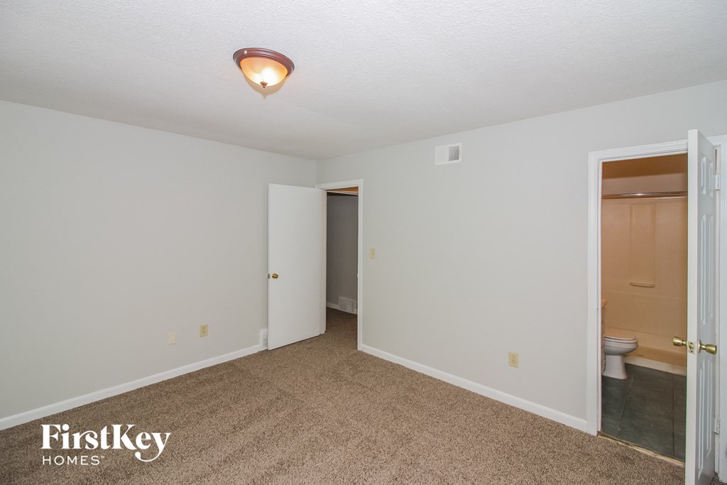 a master bedroom with a door to the bathroom and a closet