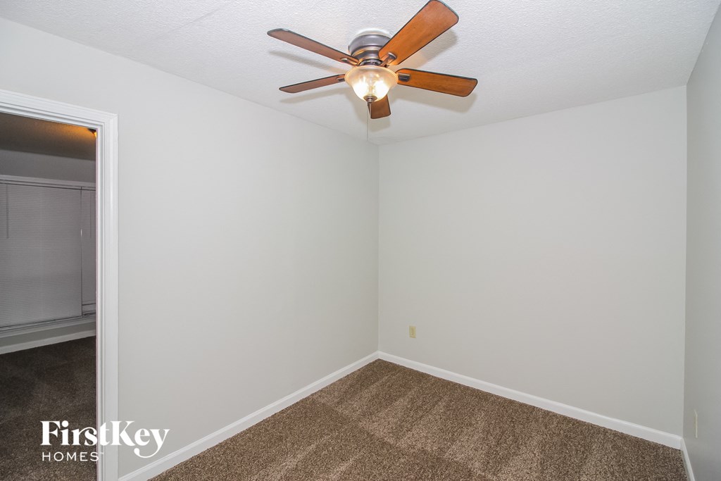 a bedroom with a ceiling fan and a carpet