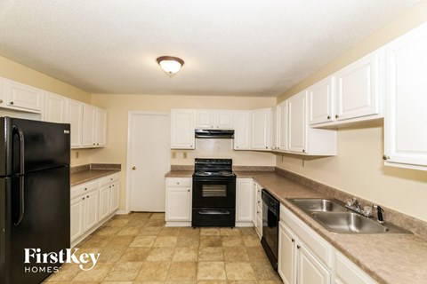A kitchen with black appliances and white cabinets.