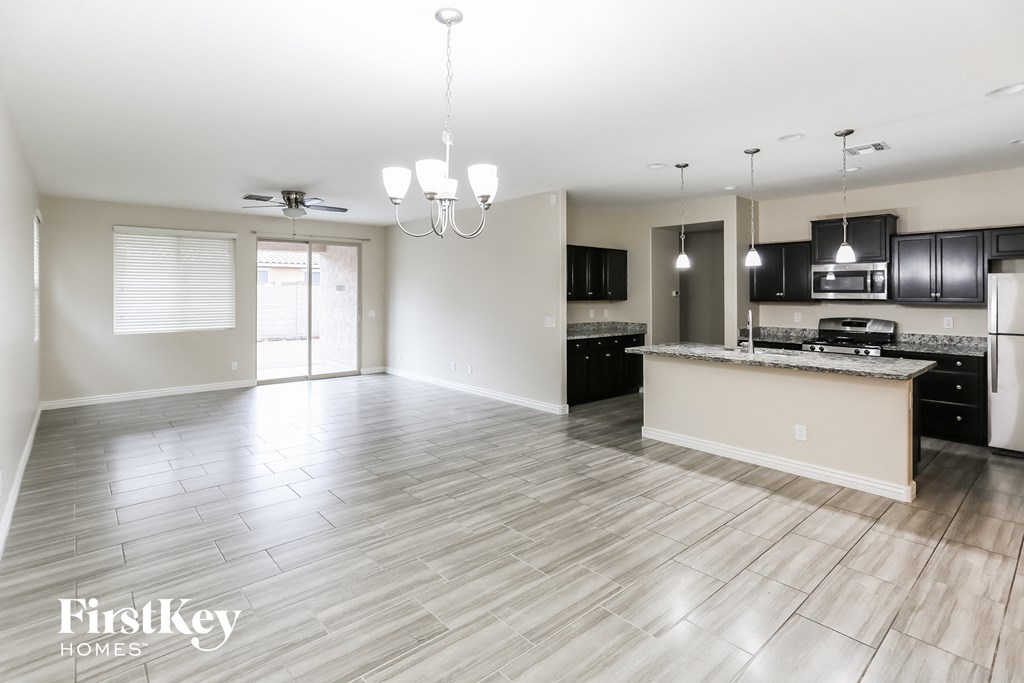 an empty kitchen and living room with wood floors and black appliances