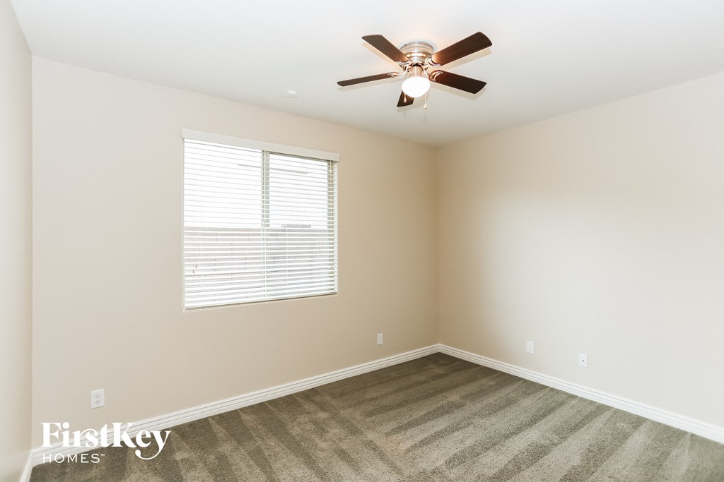 an empty room with a ceiling fan and a window
