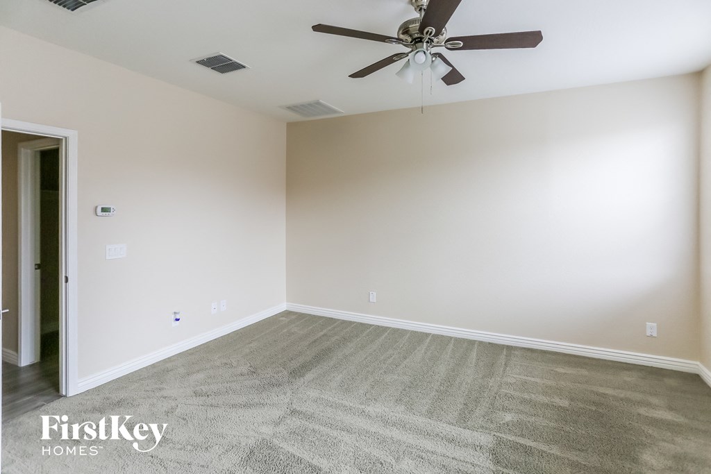 a empty living room with carpet and a ceiling fan