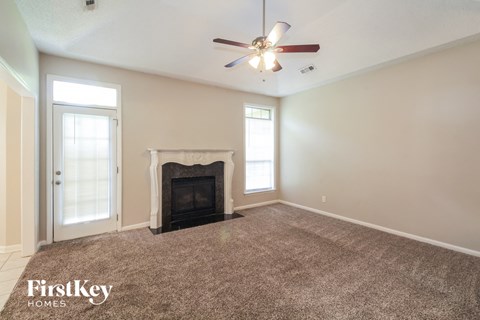 A living room with a fireplace and a ceiling fan.