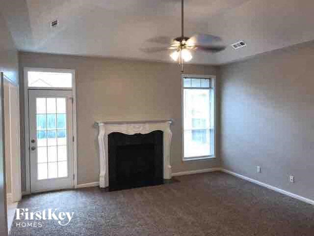 A living room with a fireplace and a ceiling fan.