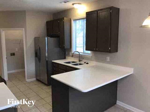 A kitchen with a white countertop and dark brown cabinets.