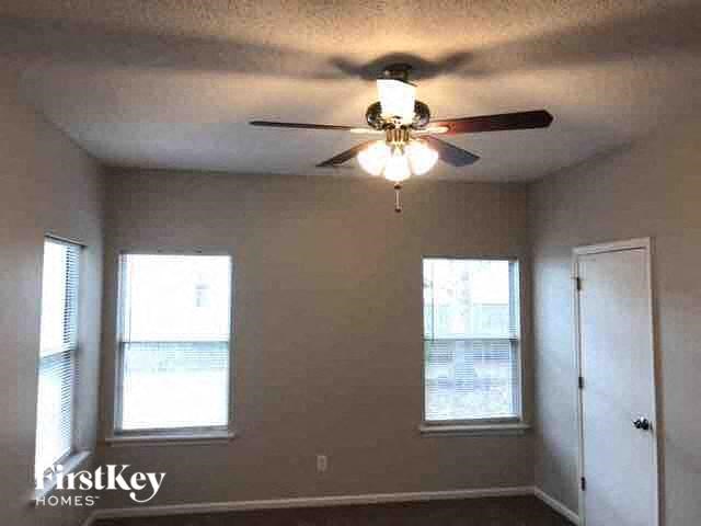 A room with a ceiling fan and two windows.