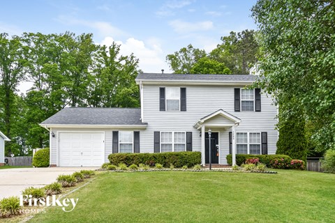 a white house with black shutters and a lawn
