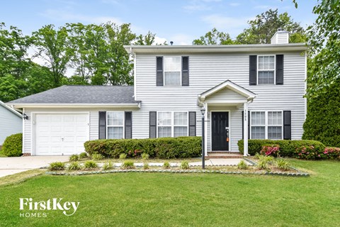 a white house with black shutters and a lawn