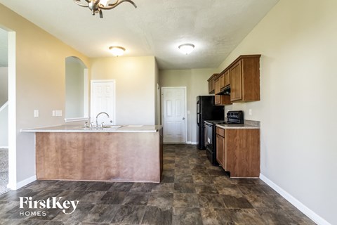 A kitchen with a wooden island and a black fridge.