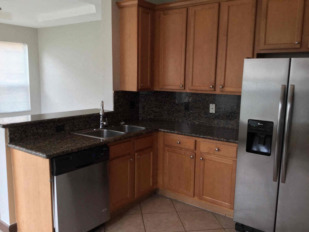 a kitchen with granite counter tops and a stainless steel refrigerator