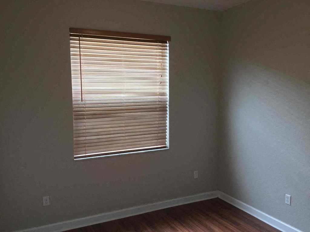 an empty room with a window with blinds on it
