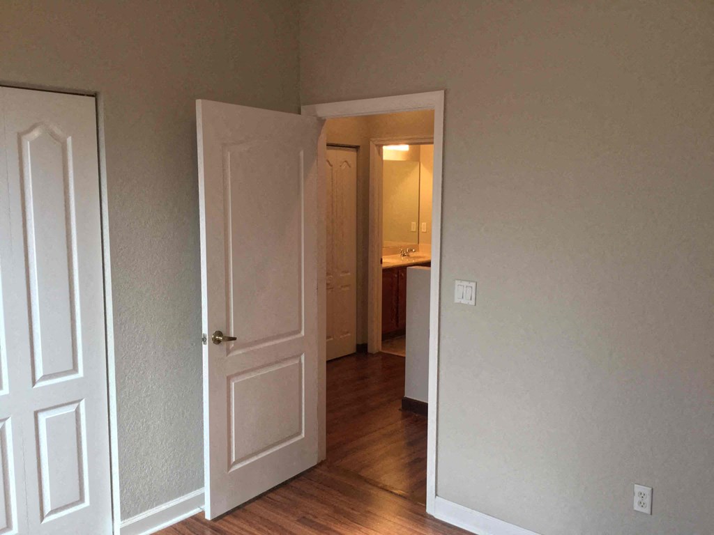 a bedroom with a door open to a hallway and a bathroom