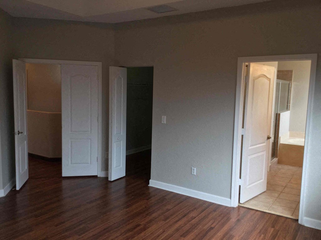 an empty living room with three doors and a wood floor