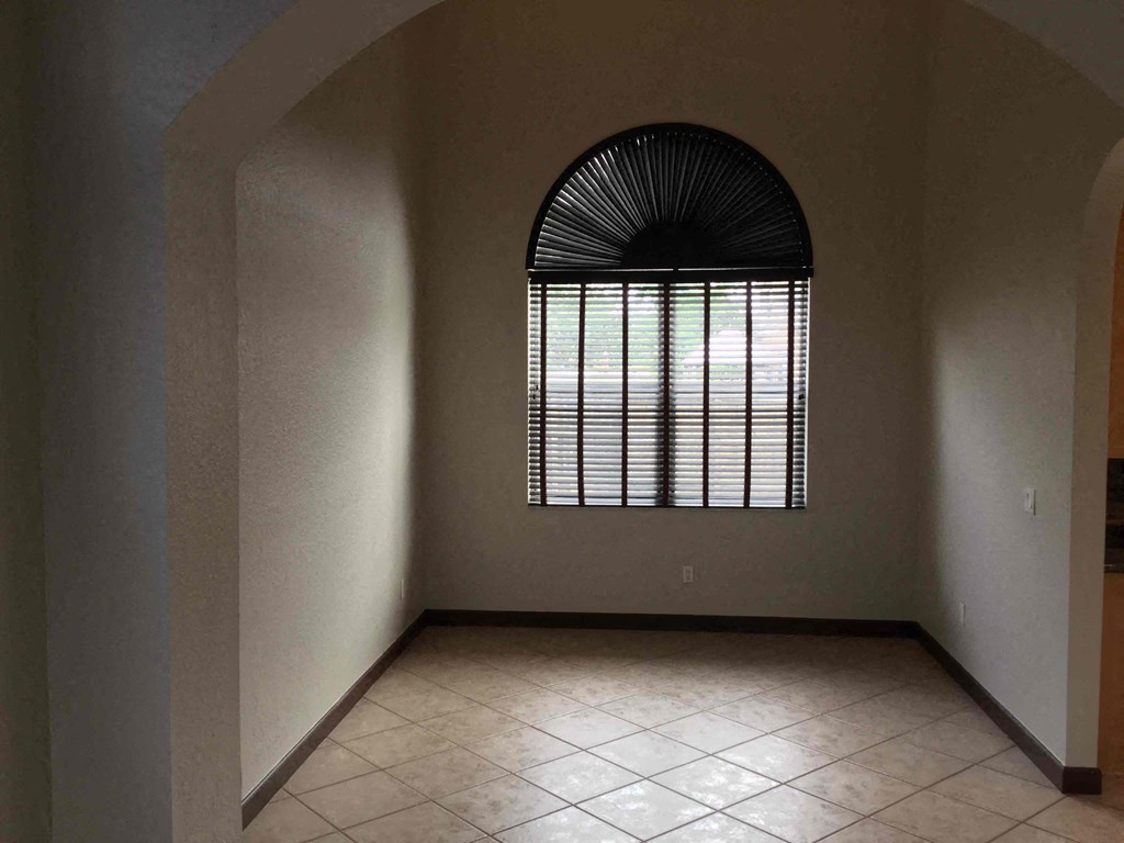 an empty room with a large window and a tiled floor