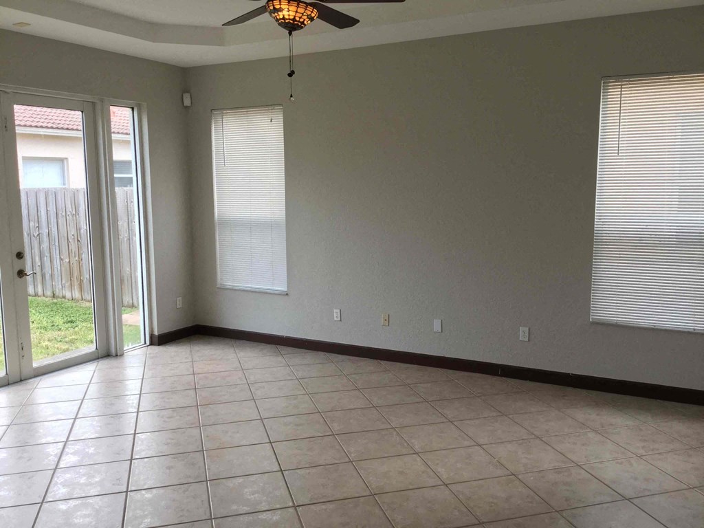 an empty living room with a ceiling fan and a tiled floor