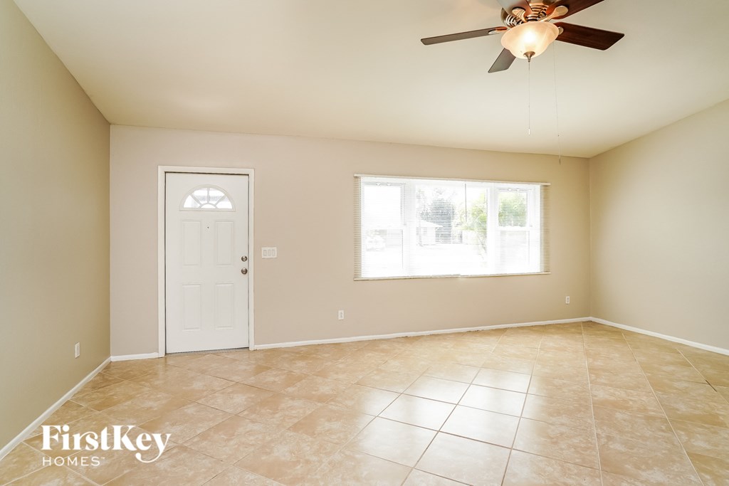 an empty living room with a ceiling fan and a window