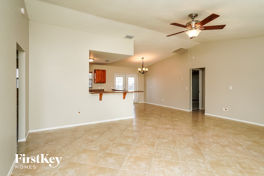 an empty living room and kitchen with a ceiling fan