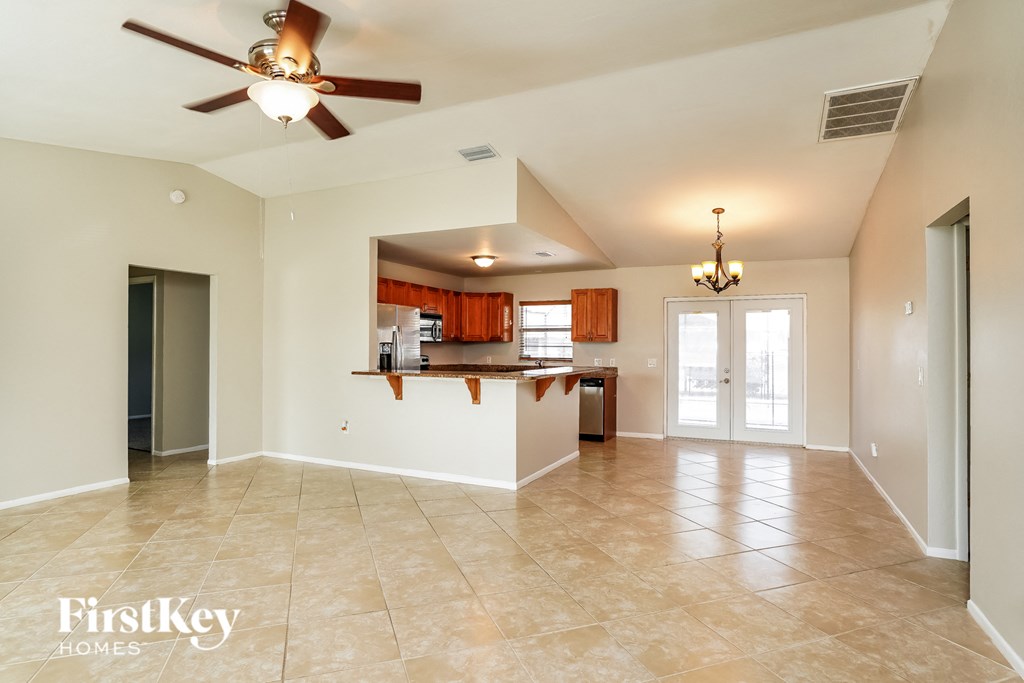 an empty living room and kitchen with a ceiling fan