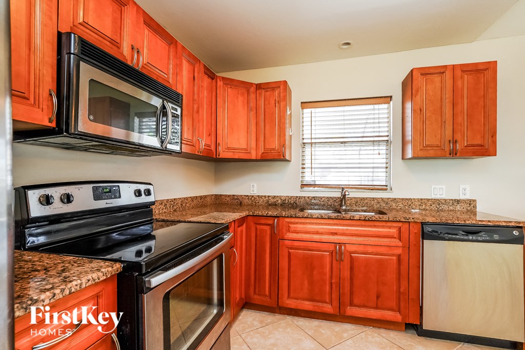 a kitchen with wood cabinets and black appliances and granite counter tops