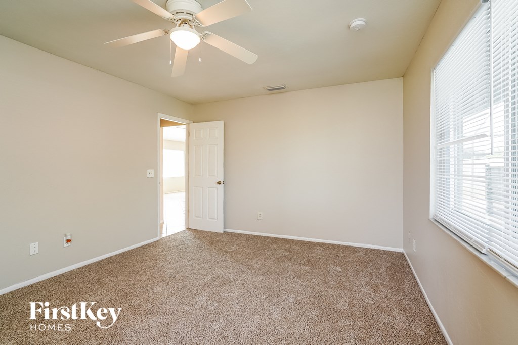 a spacious living room with a ceiling fan and window