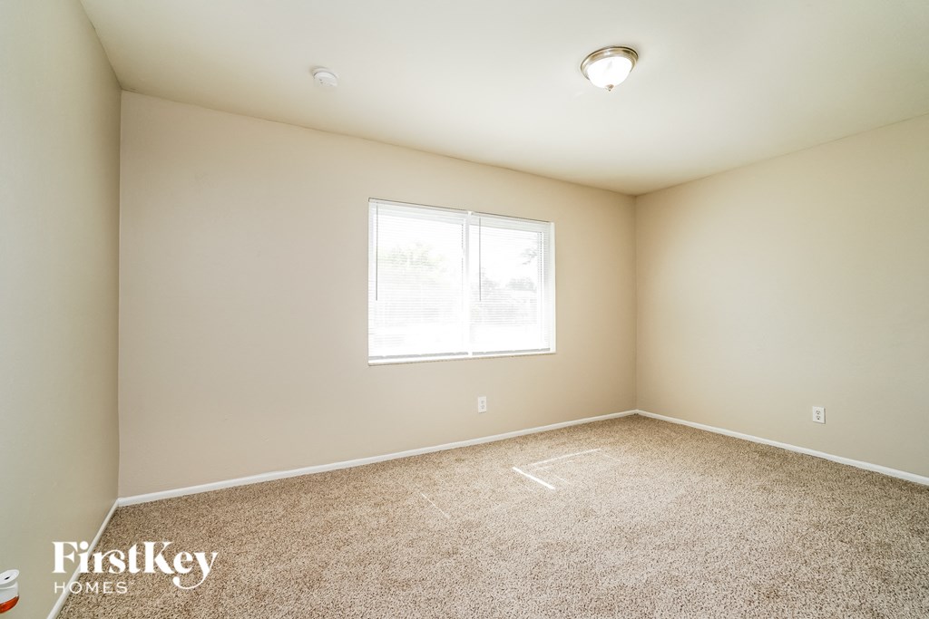 a spacious room with carpet and a window