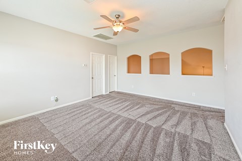 a spacious living room with carpet and a ceiling fan