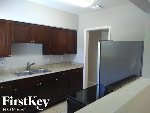 A kitchen with brown cabinets and a black fridge.