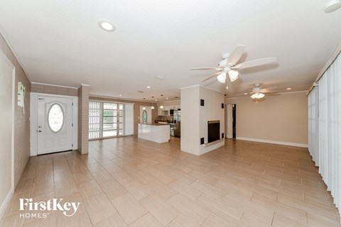 A spacious living room with a ceiling fan and lighting.