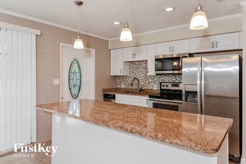 A kitchen with a granite countertop and stainless steel appliances.