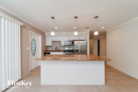 A kitchen with a white island and a fridge.