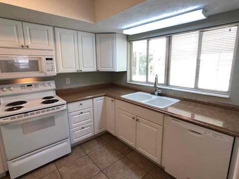 A kitchen with white cabinets and a white stove top oven.
