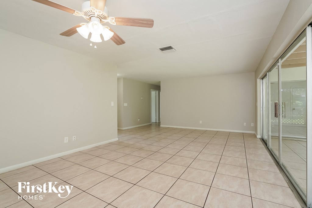 A spacious room with a ceiling fan and sliding glass doors.