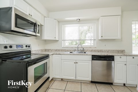 A kitchen with white cabinets and a black stove top oven.