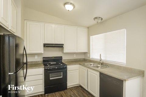 A kitchen with white cabinets and a black fridge.