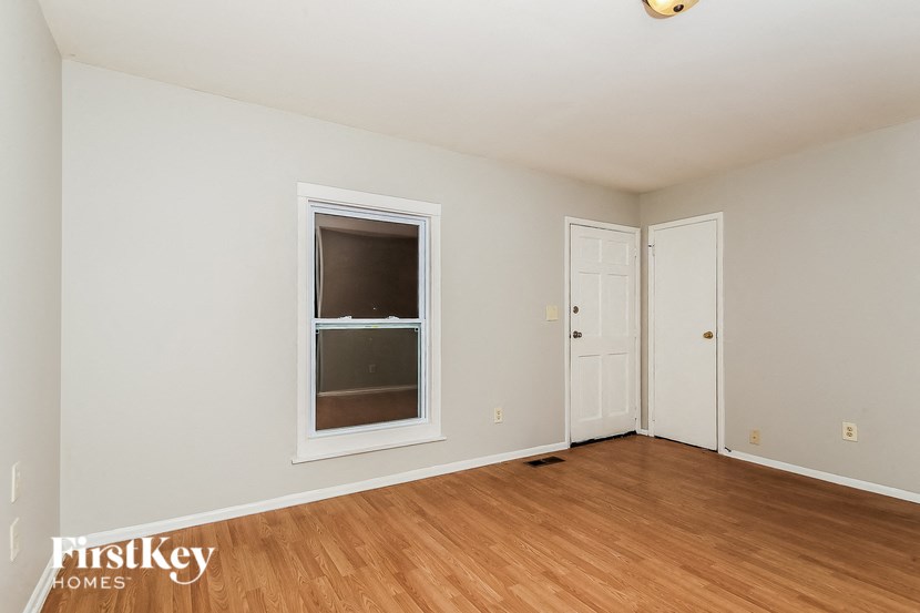 a bedroom with white walls and a window and wooden floors