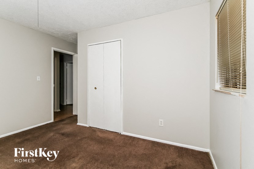 a bedroom with a carpeted floor and a door to a closet