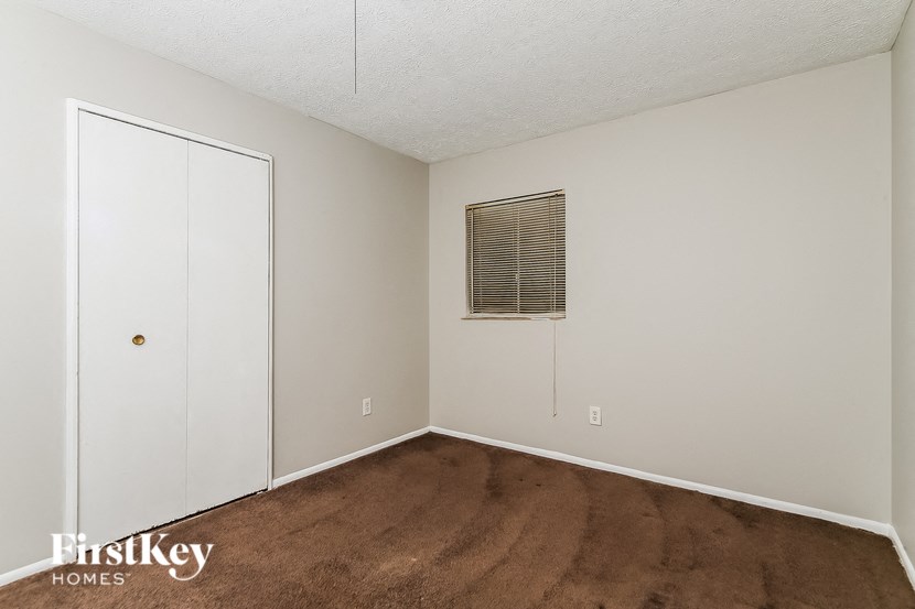 a bedroom with a carpet and a door to a closet