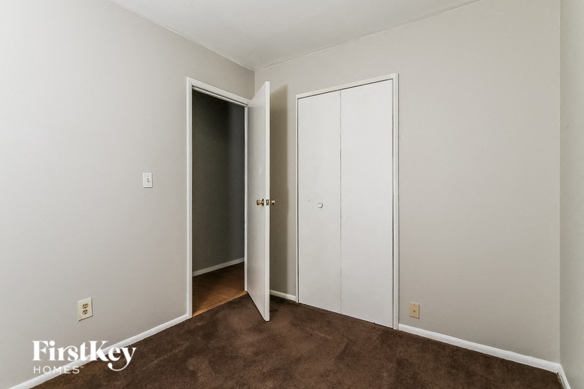 a bedroom with white walls and a door to a closet