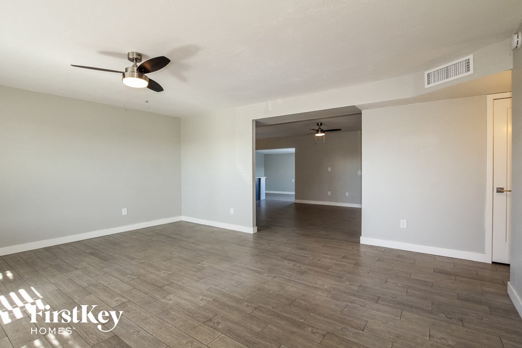 an empty living room with a ceiling fan and wood flooring