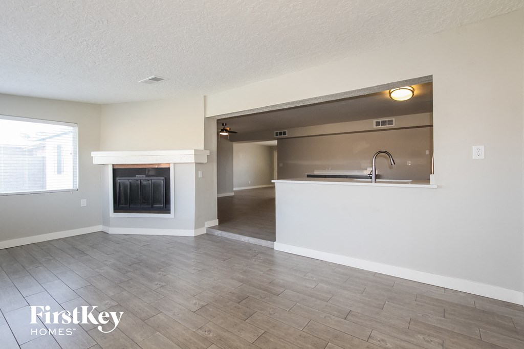 an empty living room with a fireplace and a kitchen