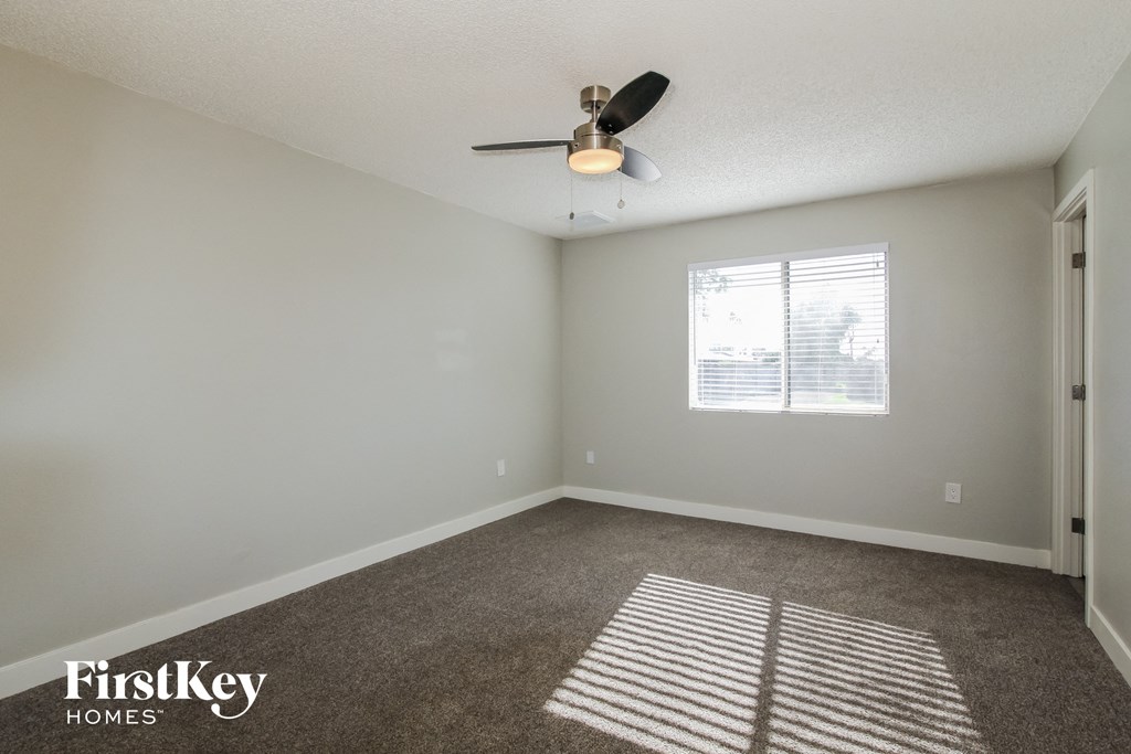 an empty living room with a ceiling fan and a window