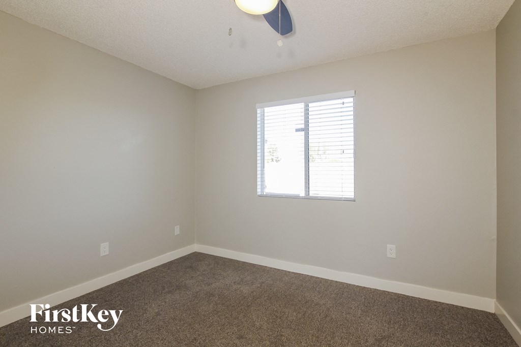 a bedroom with white walls and carpet and a window