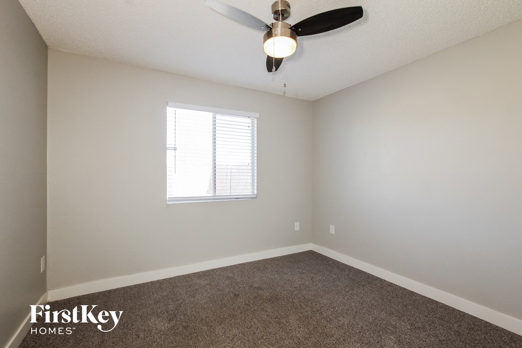 an empty room with a ceiling fan and a window