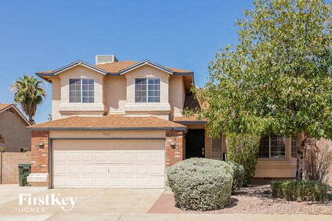 A house with a garage and a tree in front.