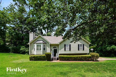 A house with a green lawn and trees in the background.