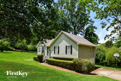 A house with a green lawn and trees in the background.